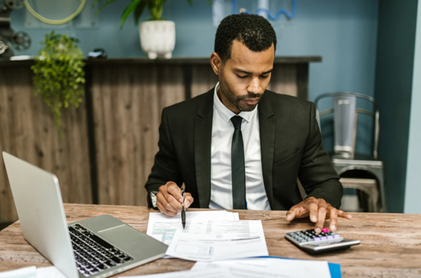Business professional working on a laptop with financial documents, representing the future of accounting industry driven by technology.