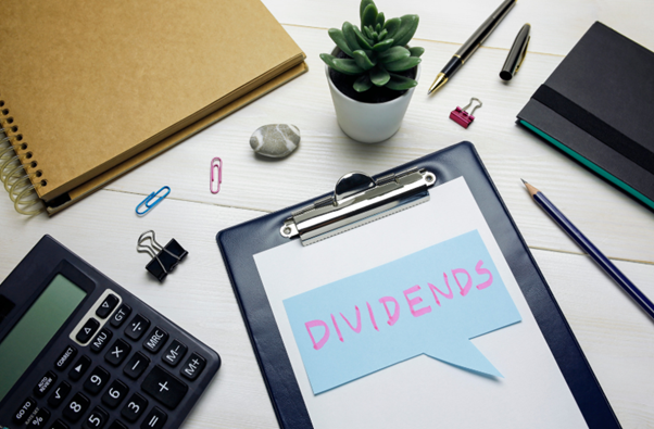 Clipboard with dividends written on paper beside calculator and office stationery, relevant to understanding do you pay national insurance on dividends.