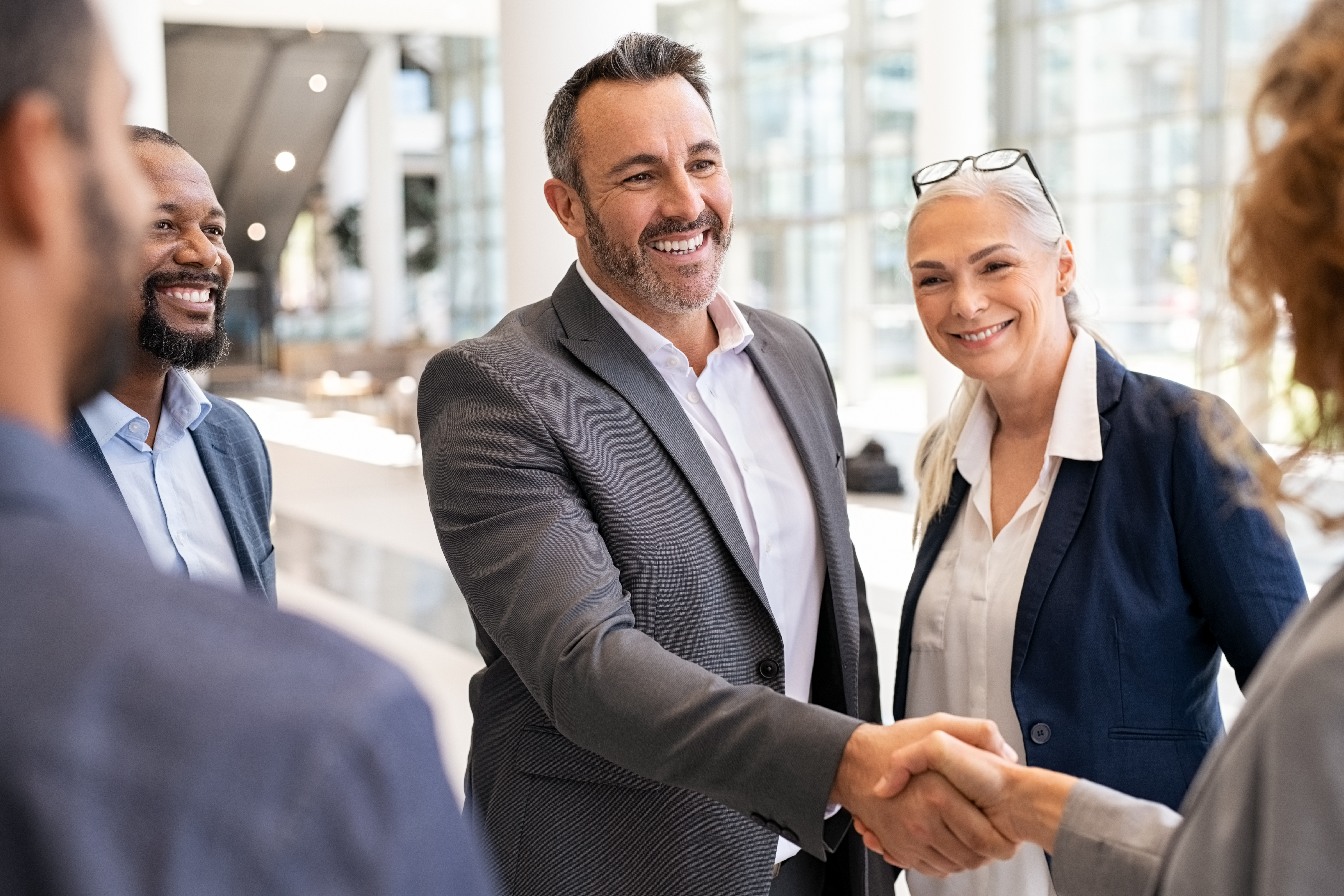 Business professionals shaking hands and smiling, forming professional partnerships for a subsidiary business.