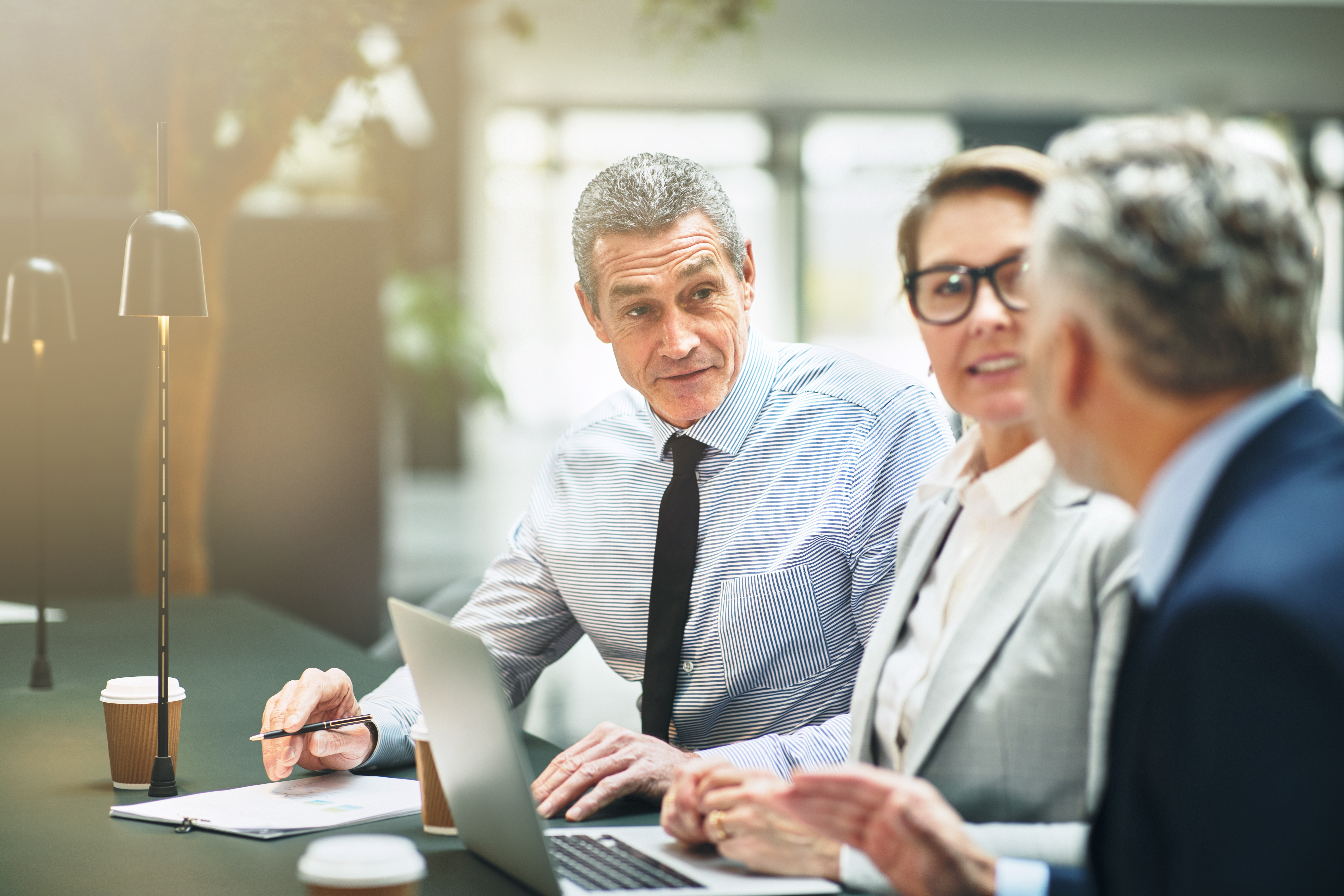 Three business professionals reviewing financial data, discussing what annual turnover means for their company's performance.